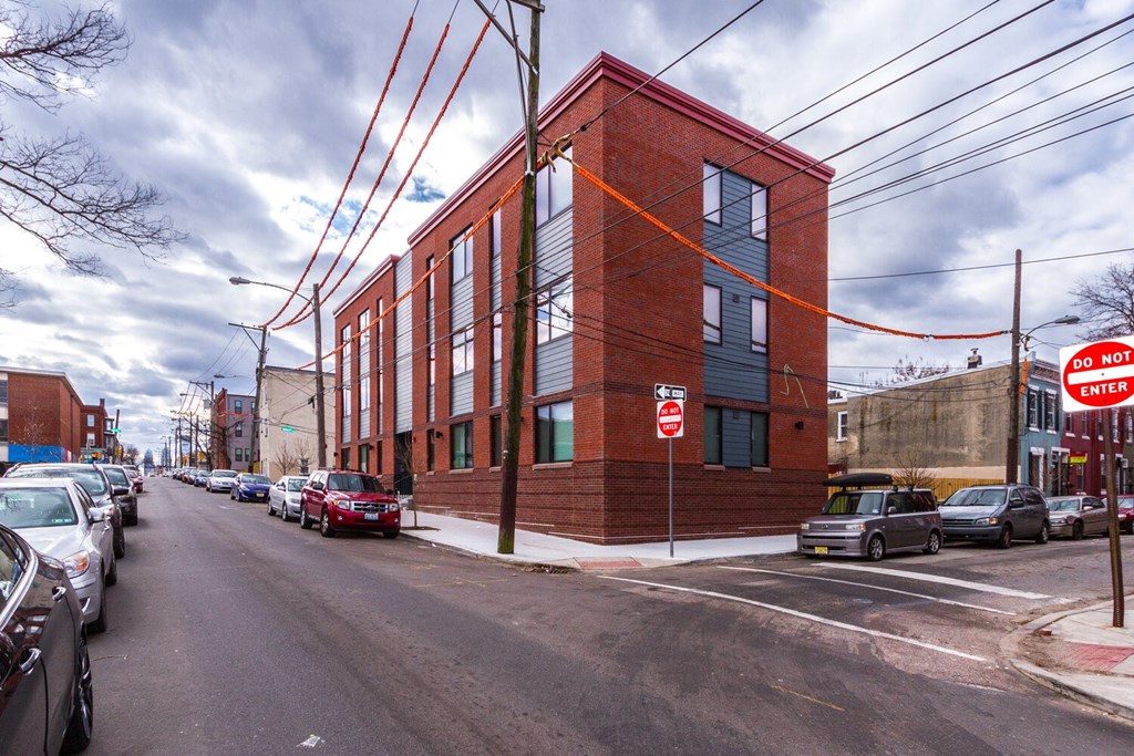 a red brick building on the corner of a street with parked cars