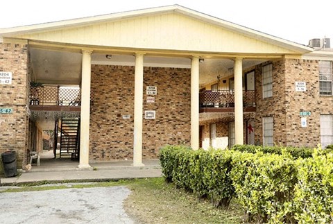 a building with pillars and a porch with bushes