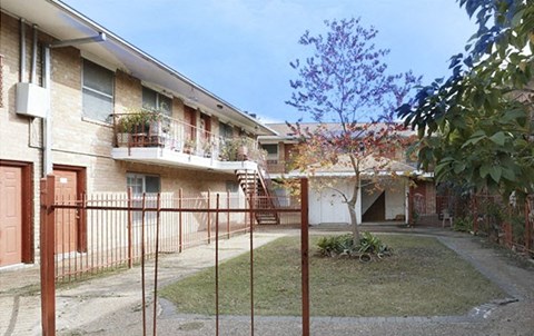 an apartment building with a yard and a fence