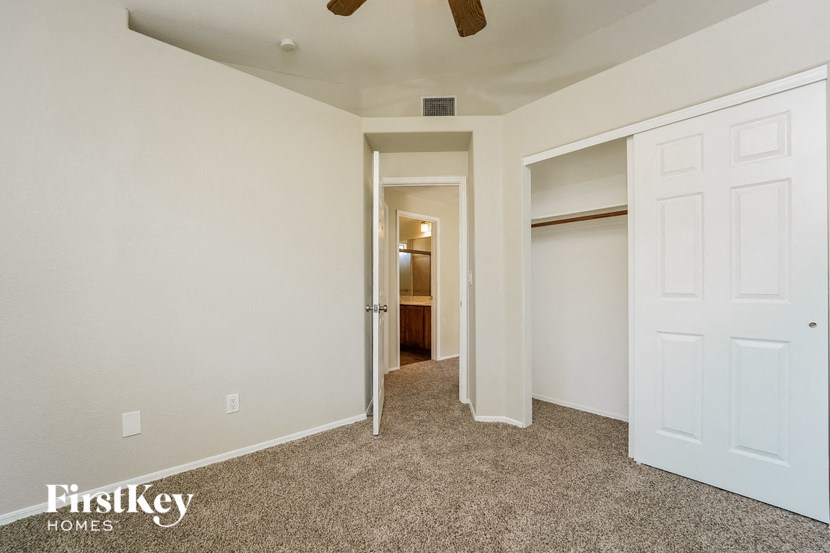 an empty bedroom with a closet and a ceiling fan