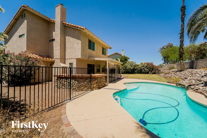 a pool in front of a house with a wrought iron fence