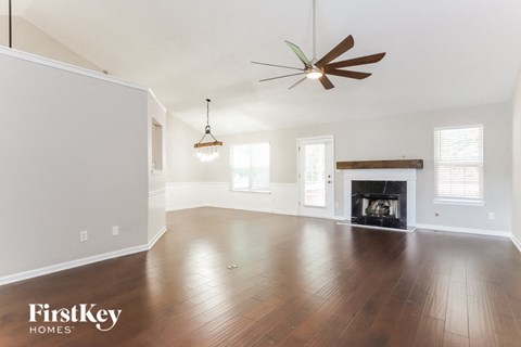 A spacious living room with a fireplace and a ceiling fan.