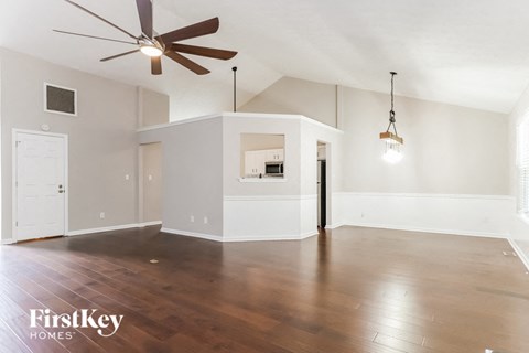 A spacious room with a ceiling fan and wooden flooring.