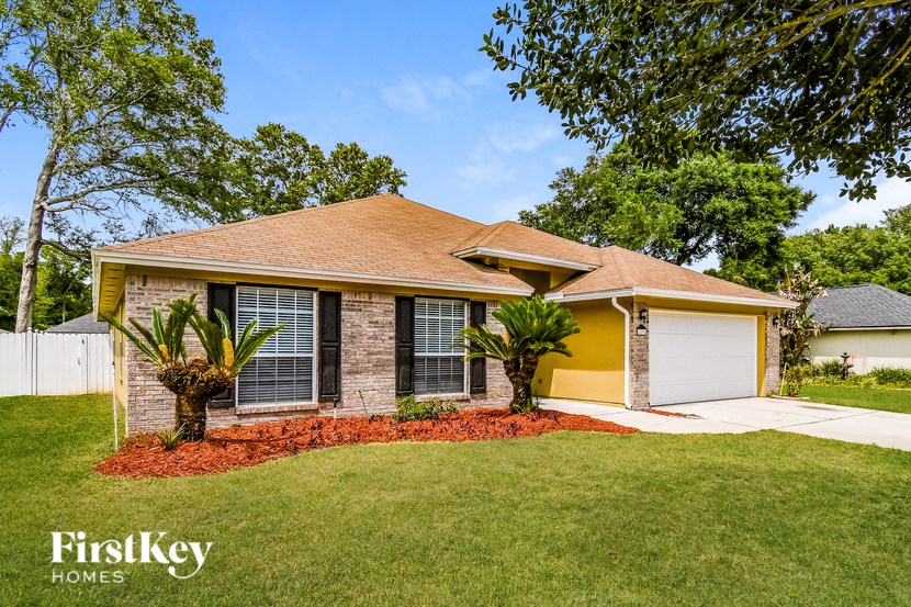 a small brick house with a lawn and palm trees
