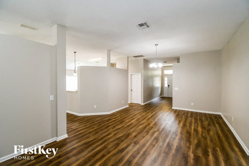 the living room and dining room of an apartment with wooden floors and white walls