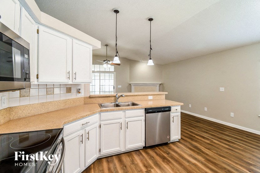 a kitchen with white cabinets and a stainless steel dishwasher and sink