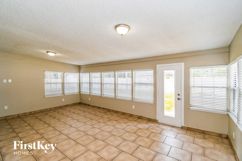 a living room with large windows and a tiled floor