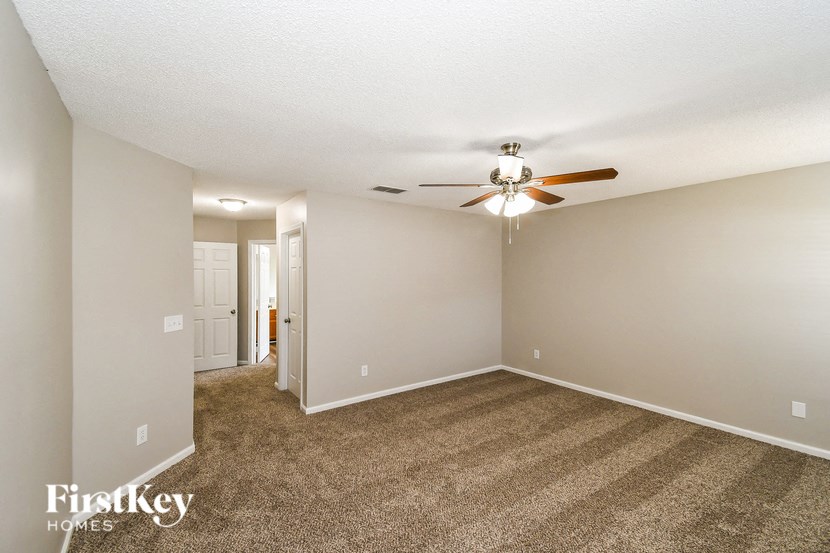 a spacious living room with carpet and a ceiling fan