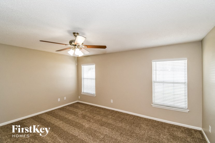 the spacious living room with carpet and a ceiling fan