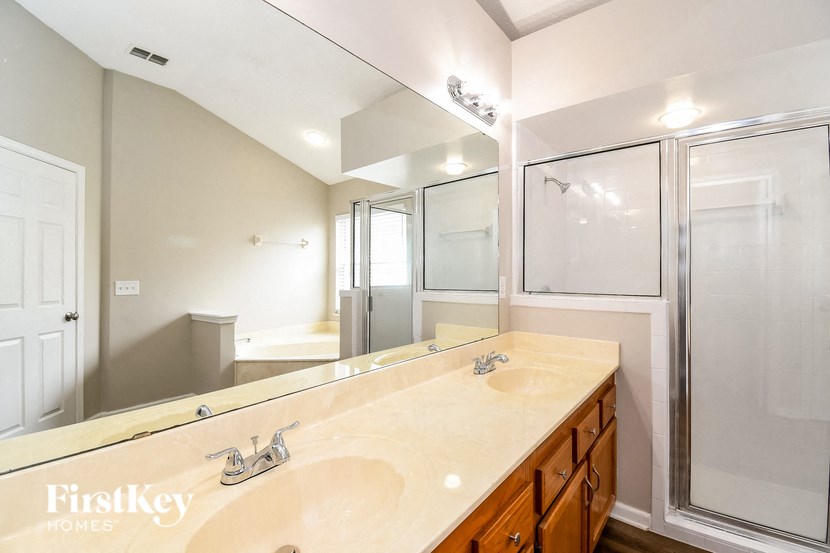 a bathroom with two sinks and a shower and a large mirror