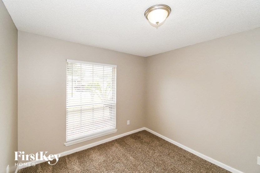 a bedroom with a large window and a carpeted floor