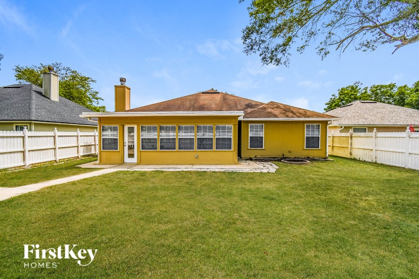 a yellow house with a yard and a white fence
