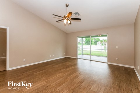 an empty living room with wood flooring and a ceiling fan