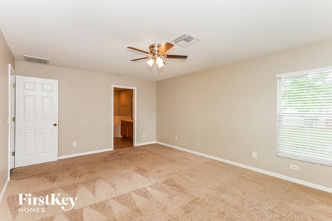 a living room with a ceiling fan and a door to a bathroom