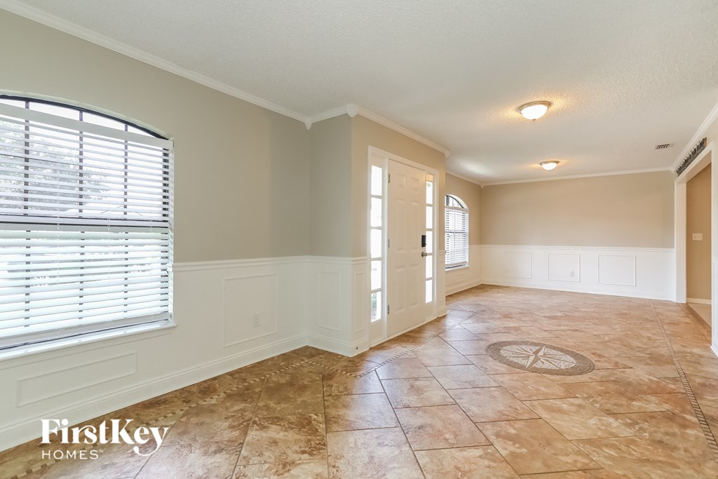 an empty living room with a large window and tiled floors