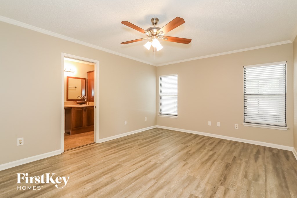 the spacious living room with hardwood flooring and a ceiling fan