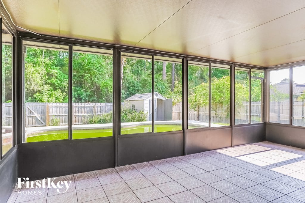 an empty living room with large windows and a view of a yard