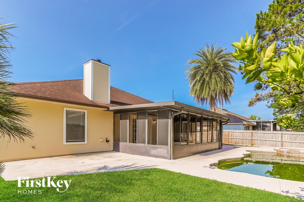 a yellow house with a pool and a palm tree