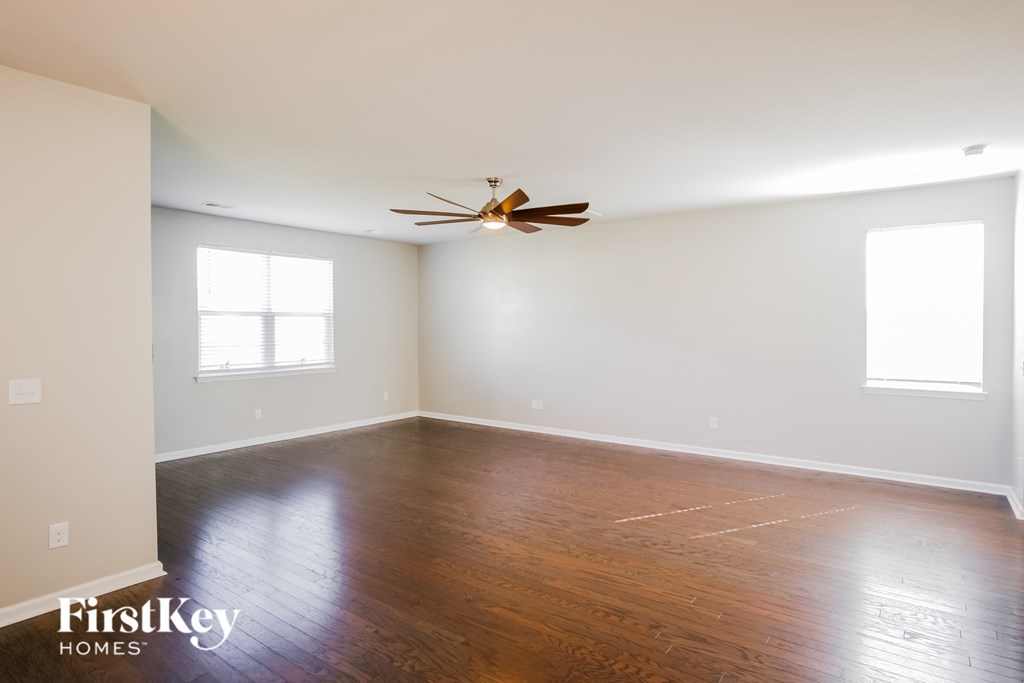 A room with a ceiling fan and two windows.