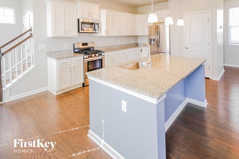 A kitchen with a granite countertop and a stainless steel refrigerator.