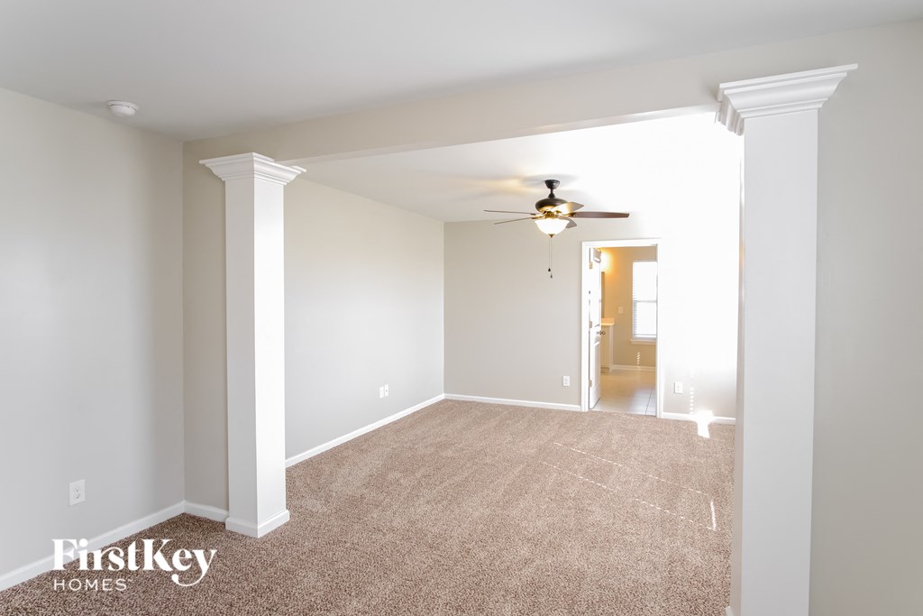 A spacious room with a carpeted floor and a ceiling fan.