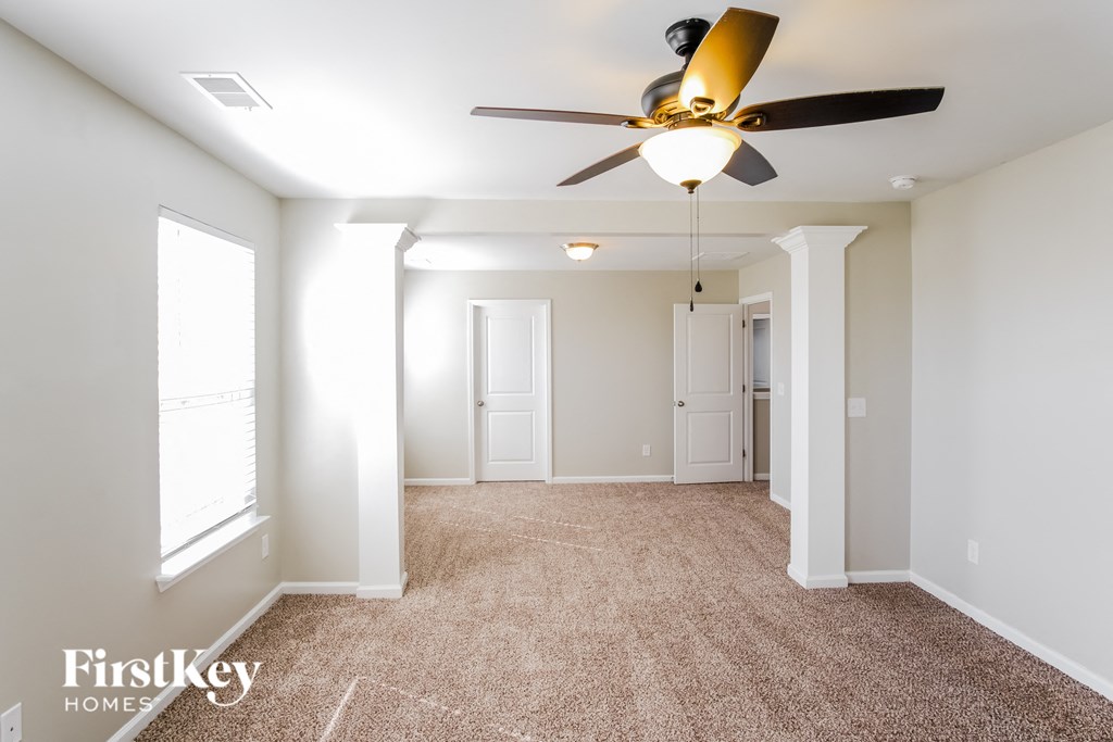 A spacious room with a ceiling fan and carpeted floor.