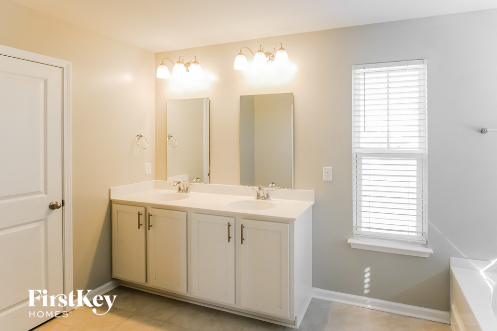 A bathroom with a double sink vanity and a large mirror.