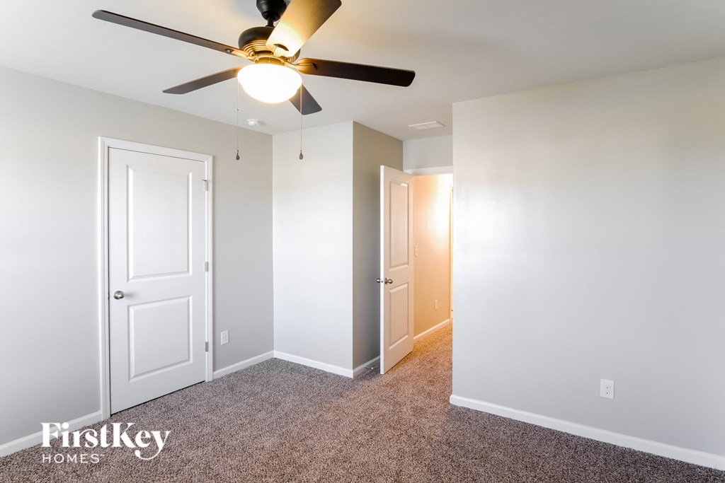A room with a ceiling fan and two doors.