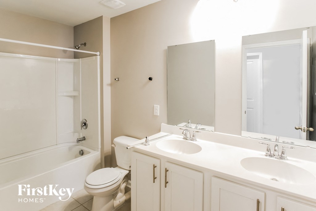A bathroom with a toilet, sink, and mirror.