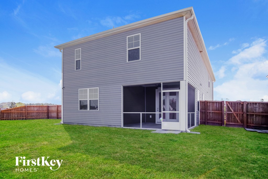 A grey house with a white door and windows is shown with a blue sky in the background.