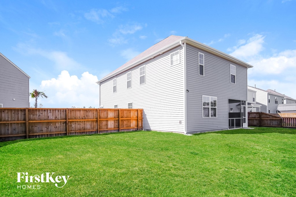 A house with a fence and a tree in the background.