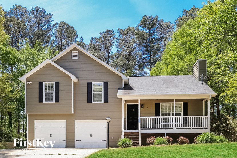 A two-story house with a garage is surrounded by trees.