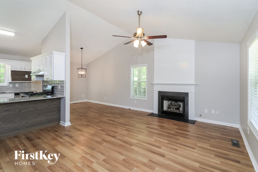A spacious living room with a fireplace and a ceiling fan.