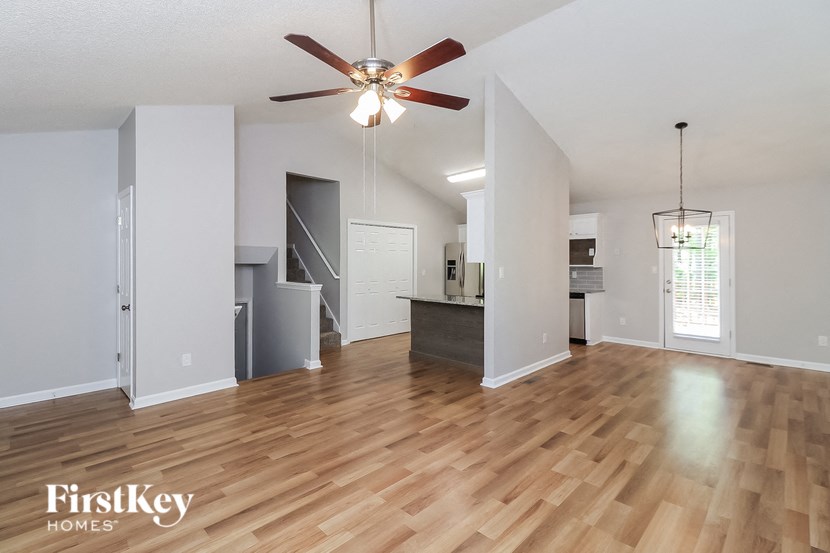 A spacious room with wooden floors and a ceiling fan.