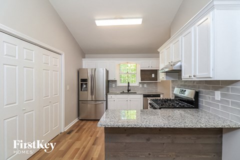 A kitchen with white cabinets and a marble countertop.
