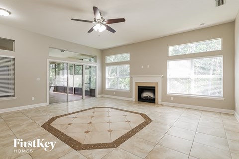 an empty living room with a fireplace and a ceiling fan