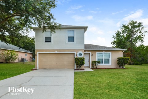 a white house with a garage door and a lawn
