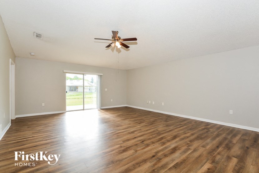 an empty living room with a ceiling fan and wood floors