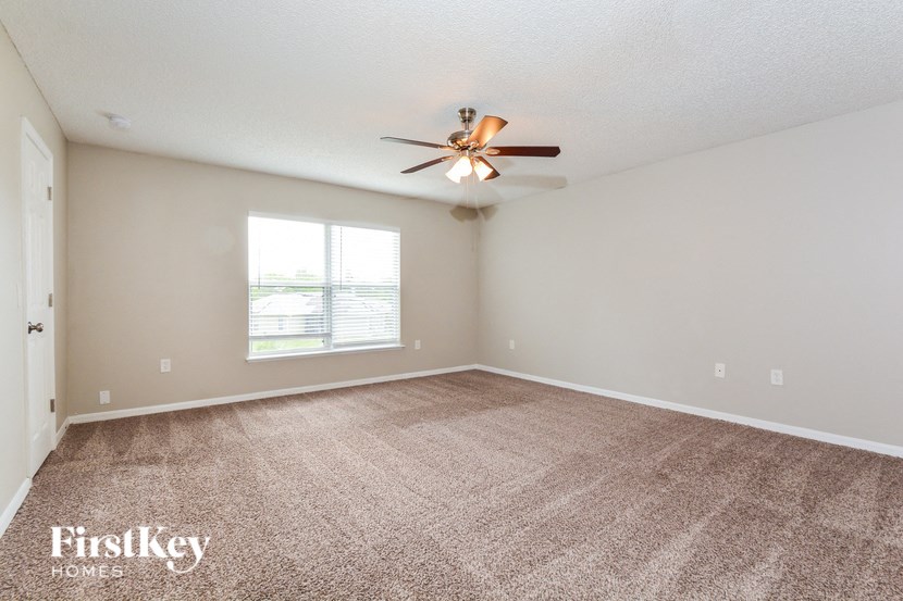 an empty living room with a ceiling fan and a window