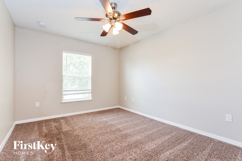 an empty living room with a ceiling fan and a window