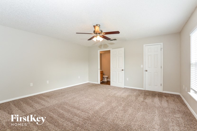 a living room with carpet and a ceiling fan