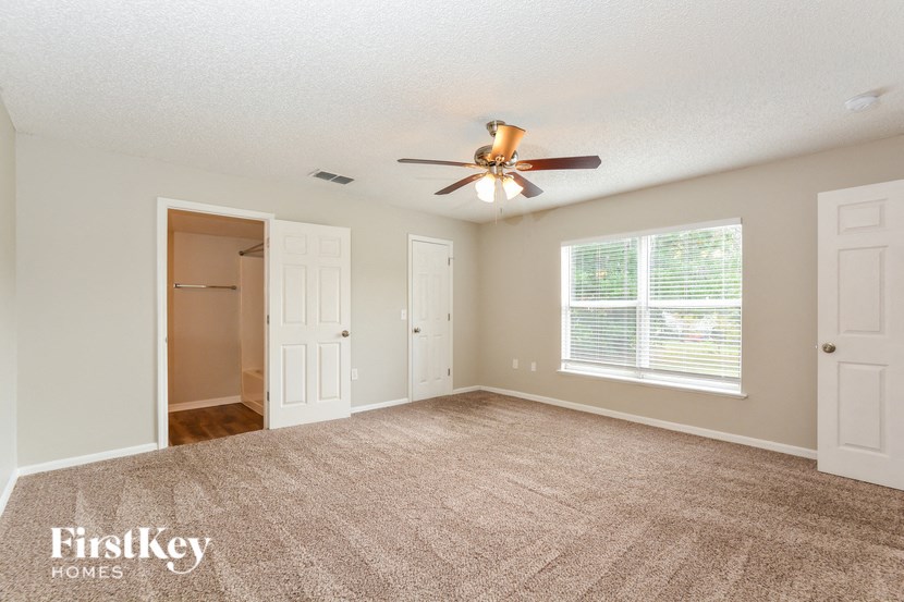 an empty living room with a ceiling fan and a closet