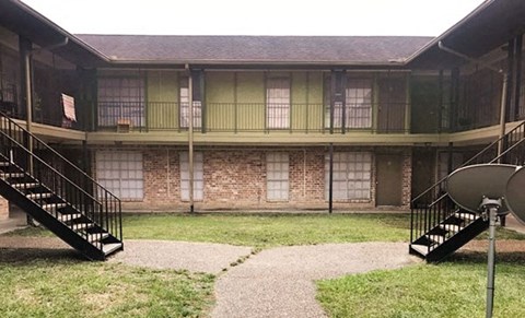 a building with stairs and a yard in front of it