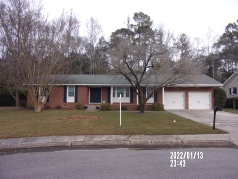 the front of a brick house with a lawn and trees