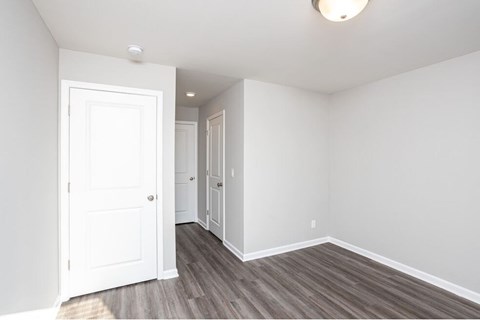 an empty bedroom with white walls and wood floors