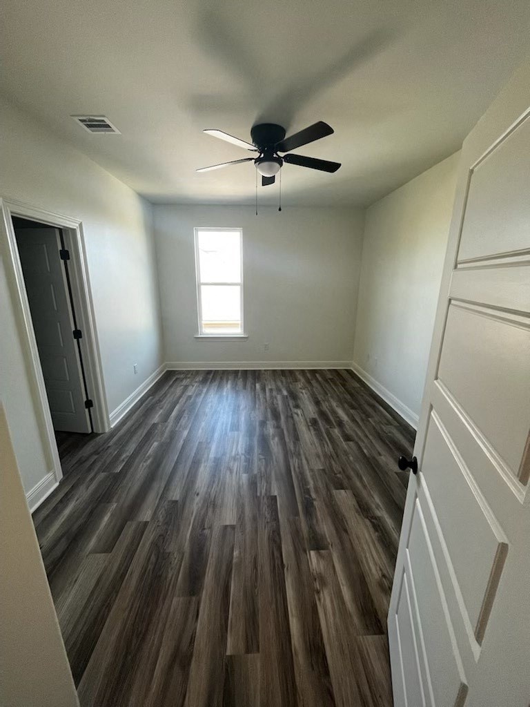 an empty room with hardwood floors and a ceiling fan