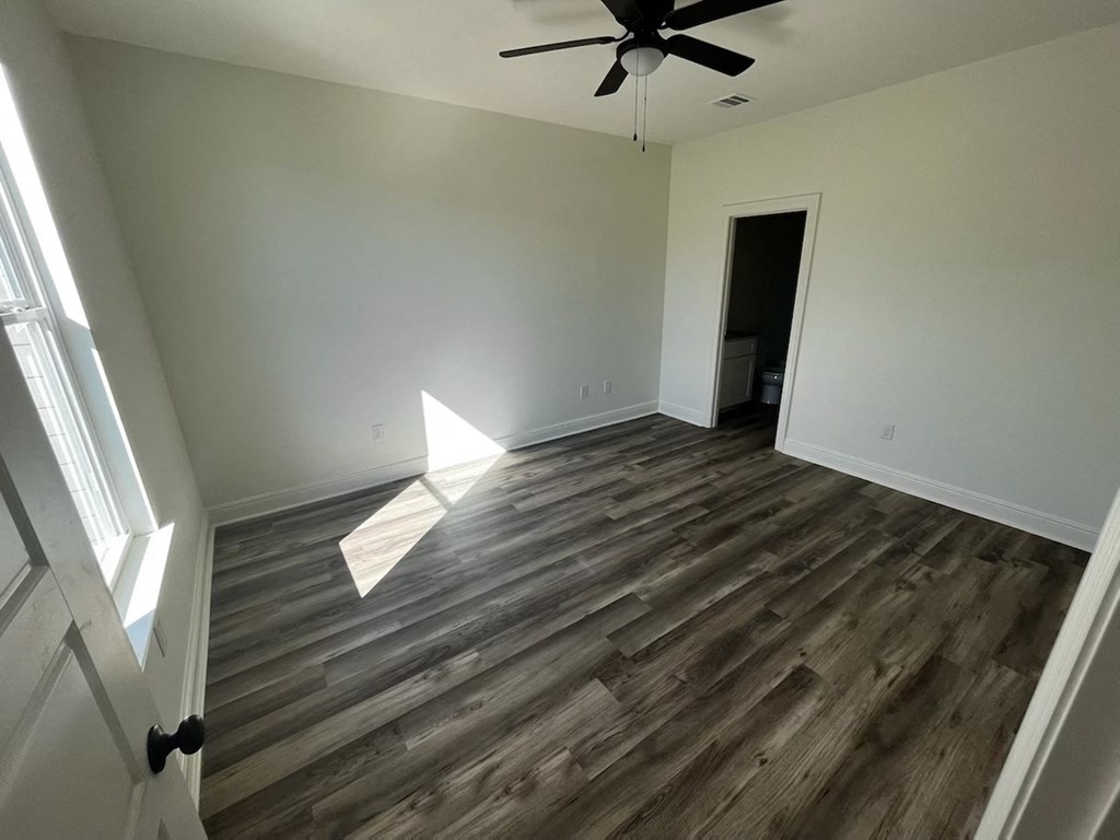 a empty living room with wood flooring and a ceiling fan