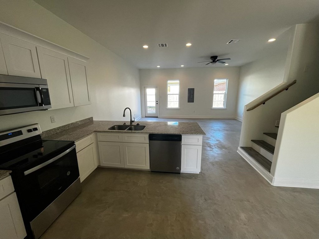 a kitchen with white cabinets and a black stove and a sink