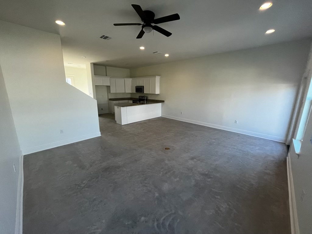 an empty living room with white walls and a ceiling fan
