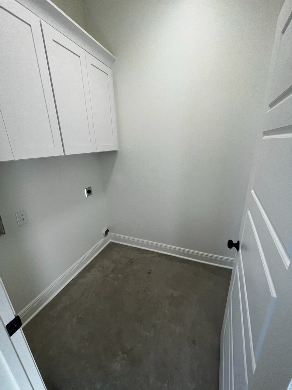 a empty room with white cabinets and a concrete floor